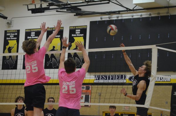 Senior Samson Schuyler attacks at the net as juniors Kelan Nicol (left) and Tommy Madden (right) attempt to block the ball in the second set of the final game.