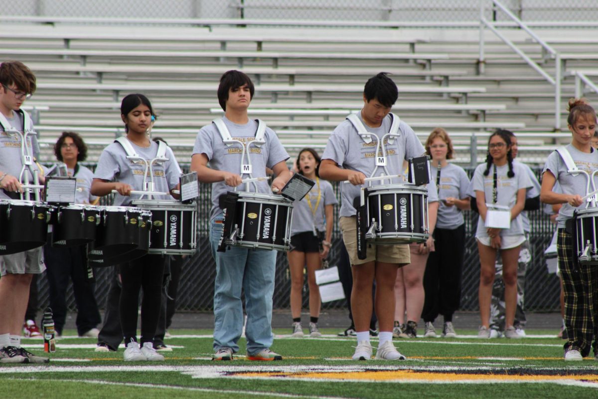 The drum section of the marching band helping make the band sound better.