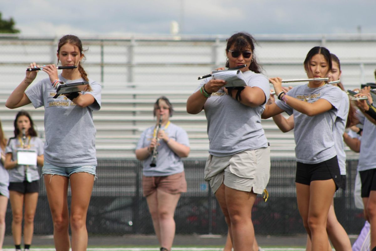 Flute players as they march along the football players elevating the marching bands performance.